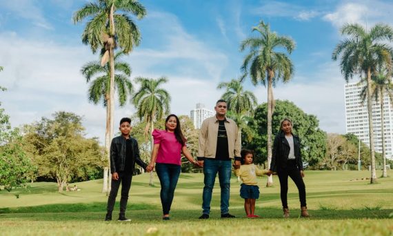 A cheerful family enjoys a sunny day in the park, surrounded by palm trees and lush greenery.