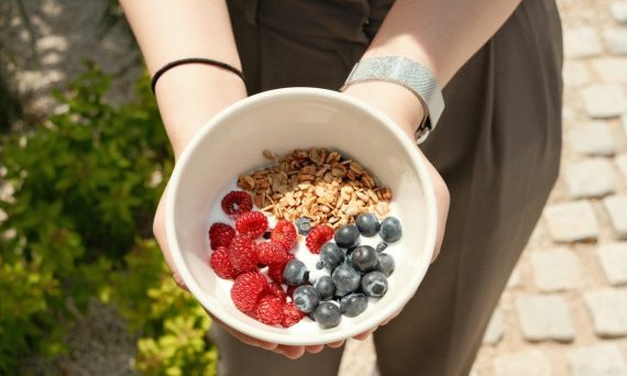 a person holding a bowl of cereal and berries